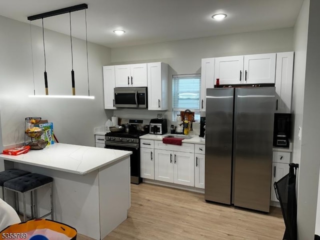86 N 7th St, Paterson City, NJ 07522 - kitchen featuring stainless steel appliances, white cabinets, a peninsula, light wood-style floors, and a kitchen breakfast bar