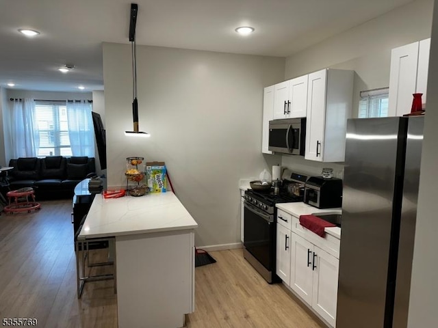 86 N 7th St, Paterson City, NJ 07522 - kitchen featuring appliances with stainless steel finishes, light countertops, light wood-style floors, a peninsula, and white cabinets