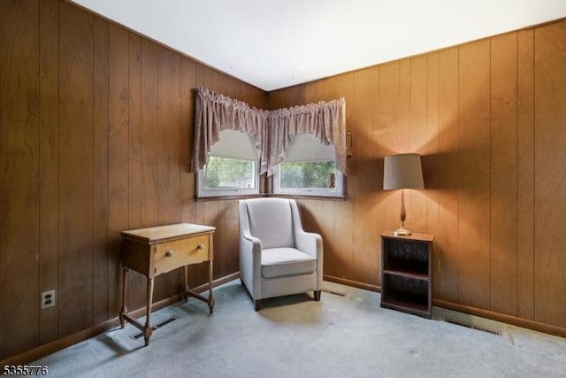 living area with carpet flooring and wood walls