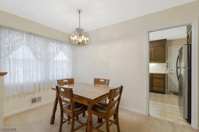 dining space featuring light carpet, a chandelier, and baseboards