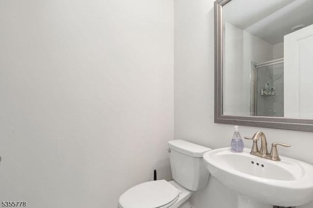bathroom with toilet, a sink, and a stall shower