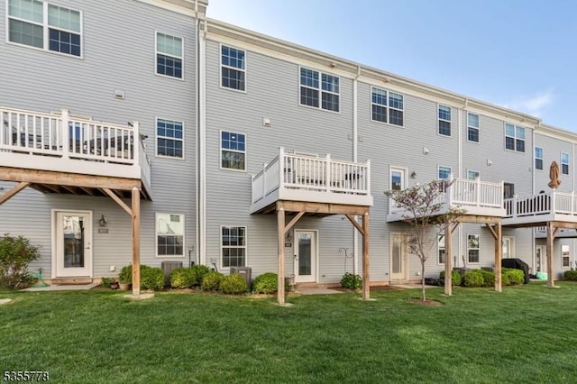 rear view of house featuring a lawn, cooling unit, and a deck