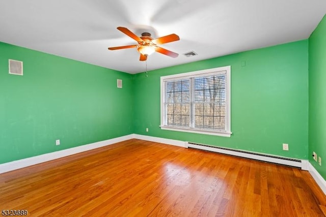 spare room featuring a baseboard heating unit, ceiling fan, baseboards, and visible vents