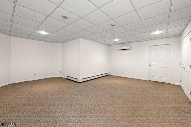 spare room featuring a wall mounted air conditioner, carpet floors, baseboard heating, a paneled ceiling, and baseboards