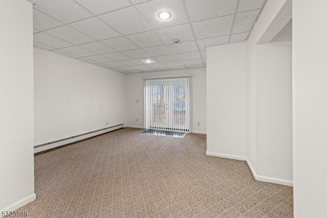 below grade area featuring a baseboard heating unit, a drop ceiling, carpet flooring, and baseboards