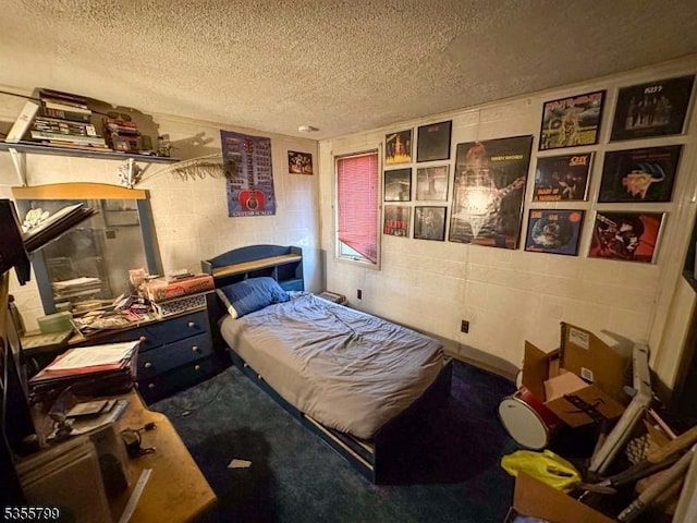 bedroom with concrete block wall and a textured ceiling