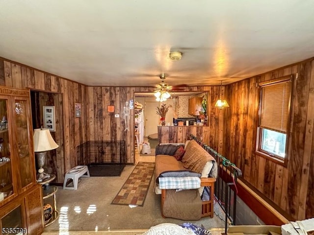 living room with wooden walls, carpet floors, and a ceiling fan