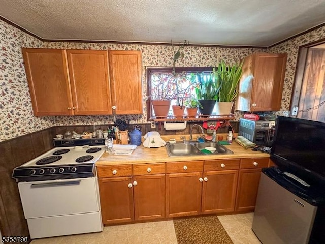 kitchen featuring wallpapered walls, white electric stove, a sink, crown molding, and brown cabinetry