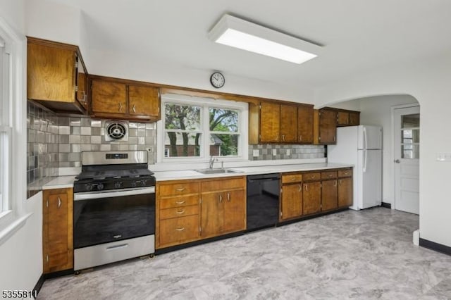 kitchen with stainless steel gas stove, black dishwasher, freestanding refrigerator, and light countertops