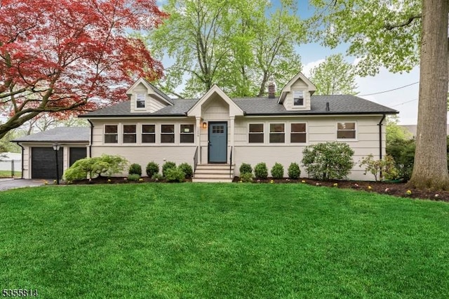 view of front of home featuring a front lawn, a garage, driveway, entry steps, and a shingled roof