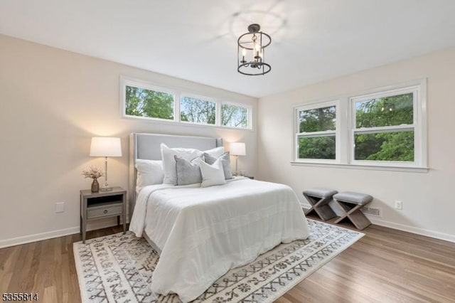 bedroom featuring baseboards, wood finished floors, and a chandelier