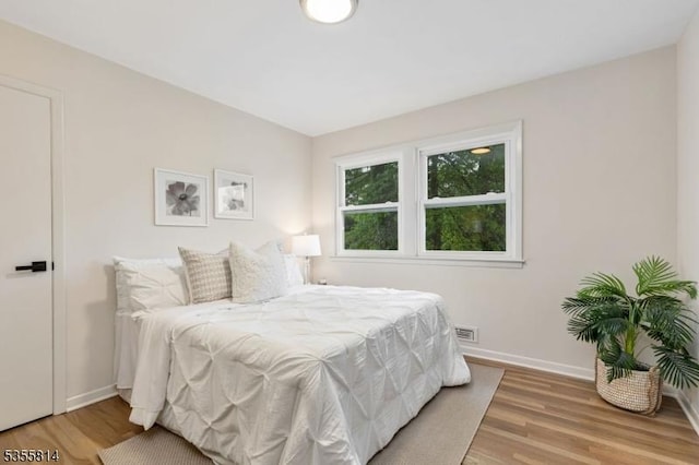 bedroom featuring light wood finished floors and baseboards