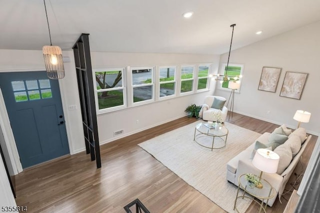 living room with healthy amount of natural light, lofted ceiling, wood finished floors, baseboards, and recessed lighting