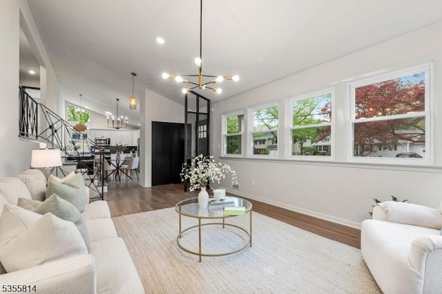 living area featuring a chandelier, dark wood-style floors, stairs, baseboards, and lofted ceiling