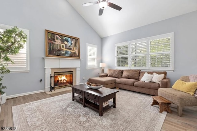 living room with a healthy amount of sunlight, wood finished floors, ceiling fan, and high vaulted ceiling