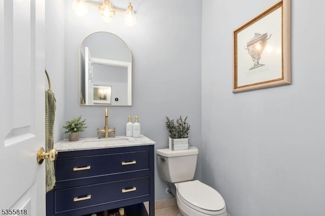 half bathroom with vanity, toilet, and baseboards