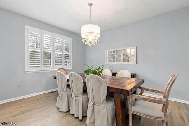 dining area featuring a chandelier, baseboards, and light wood-style floors