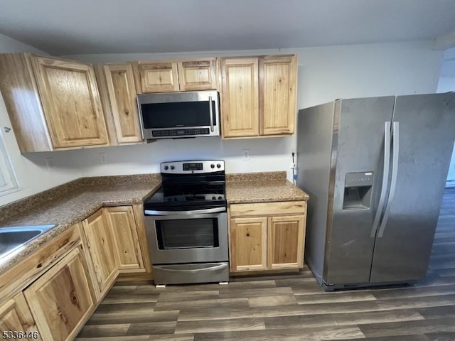 kitchen featuring dark countertops, stainless steel appliances, dark wood-style flooring, and light brown cabinetry