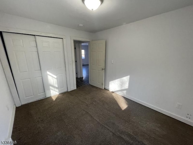 unfurnished bedroom with carpet, a closet, and baseboards