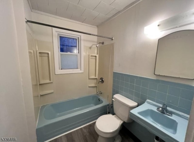 full bathroom with tile walls, toilet,  shower combination, a sink, and wood finished floors