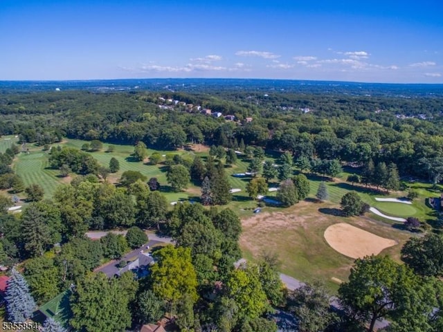 aerial view of property and surrounding area featuring a forest and a local golf course
