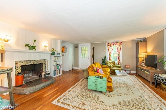 living area with wood finished floors and a fireplace with raised hearth