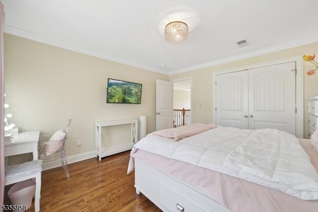 bedroom with ornamental molding, wood finished floors, a closet, and baseboards