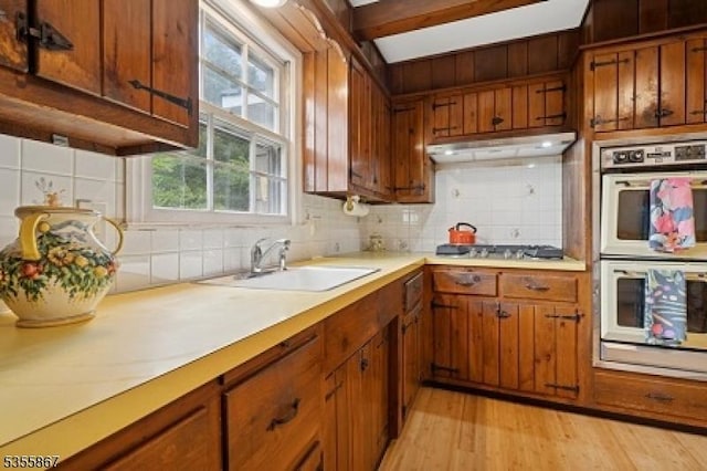 7 Fairhaven Dr, Parsippany-Troy Hills Twp, NJ 07950 - kitchen with stainless steel double oven, a sink, under cabinet range hood, decorative backsplash, and brown cabinets