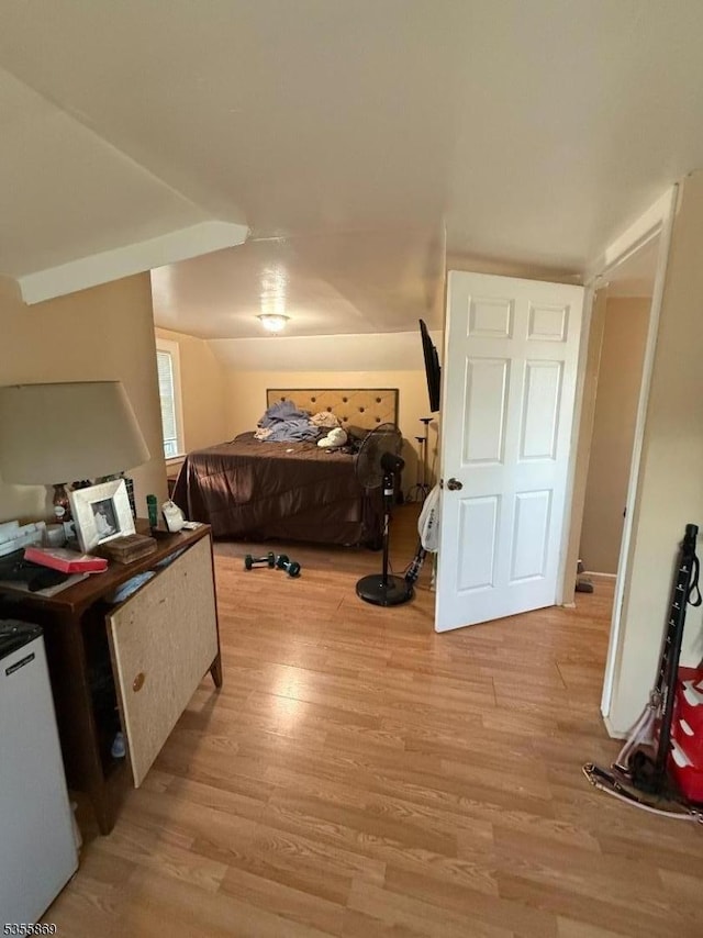 bedroom with light wood finished floors and refrigerator