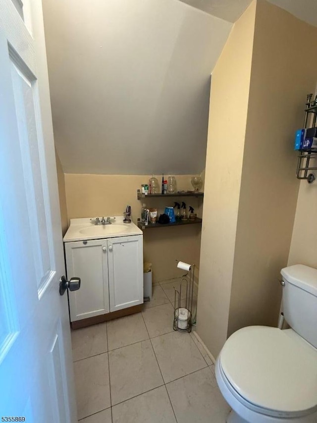 bathroom featuring toilet, vaulted ceiling, tile patterned floors, and vanity