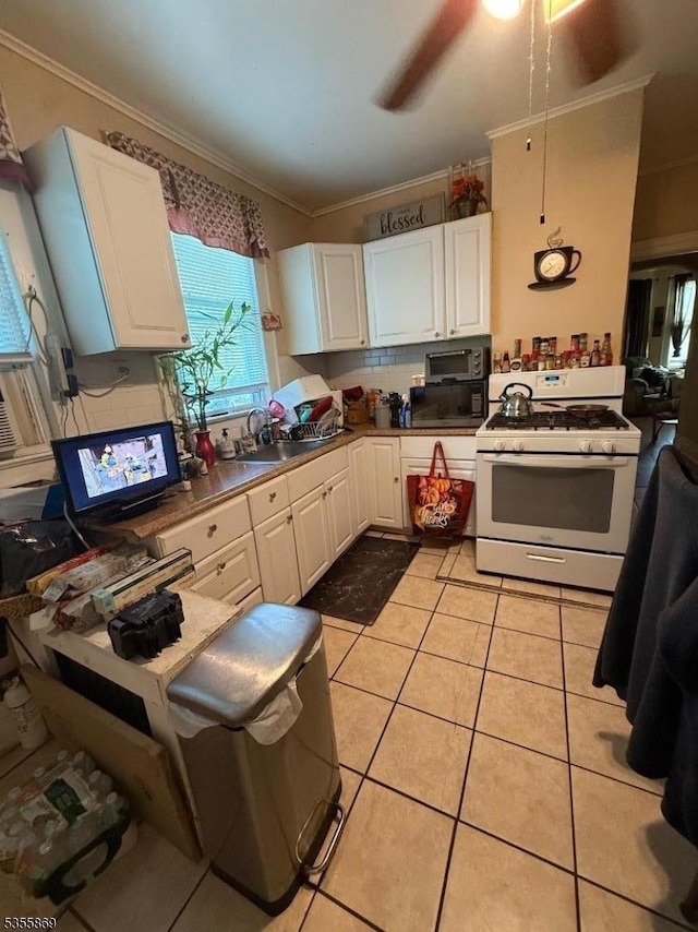 kitchen with gas range gas stove, black microwave, white cabinetry, ornamental molding, and light tile patterned floors