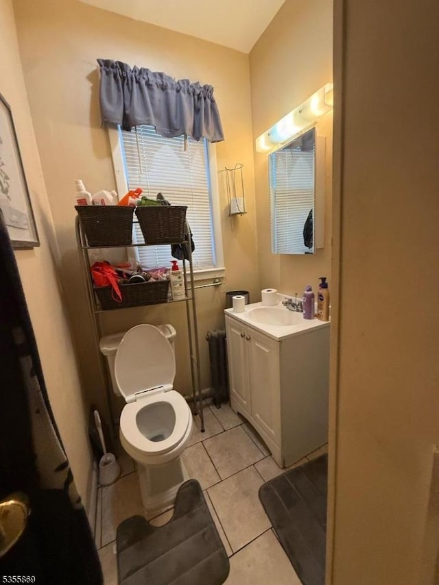 half bath featuring tile patterned flooring, vanity, and toilet