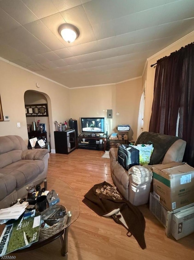 living room with crown molding, wood finished floors, and arched walkways