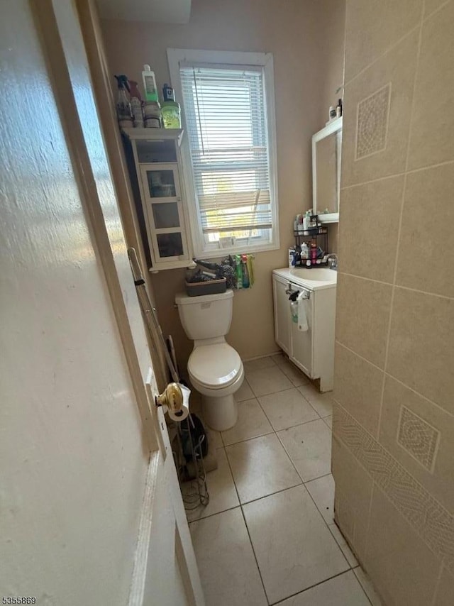 half bath with toilet, vanity, and tile patterned floors