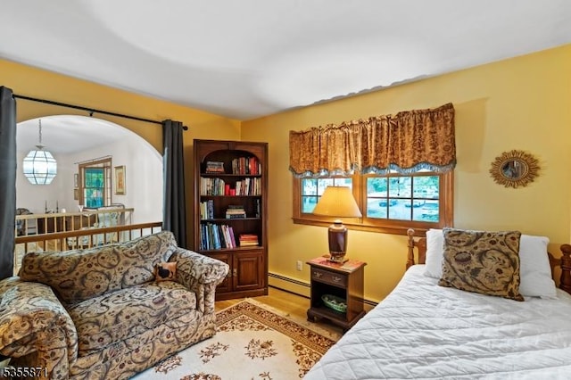 bedroom with baseboard heating, multiple windows, light wood-type flooring, and arched walkways