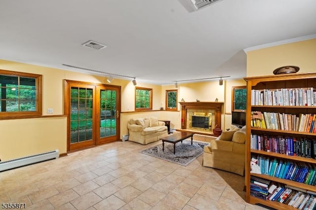 living area with rail lighting, a glass covered fireplace, plenty of natural light, crown molding, and a baseboard radiator