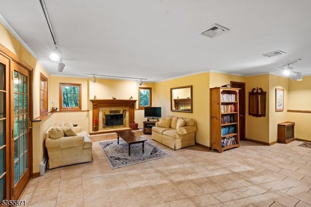 living room featuring track lighting, a glass covered fireplace, baseboards, and a baseboard radiator