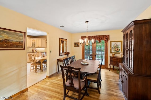 dining area with a chandelier, light wood-style flooring, and baseboards