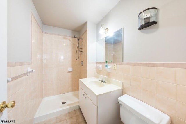 full bathroom featuring tile walls, a tile shower, toilet, and vanity