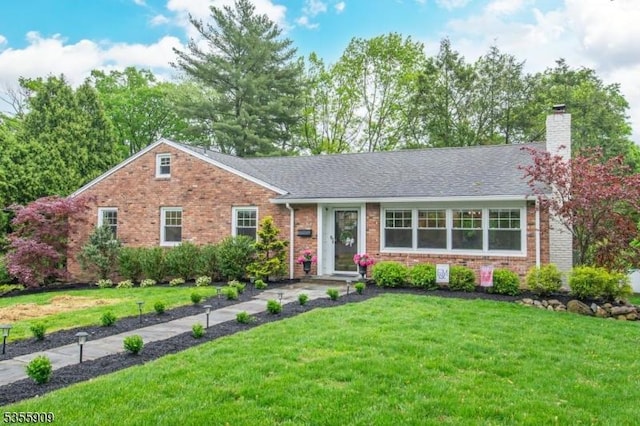 ranch-style house featuring brick siding, a front yard, and a chimney