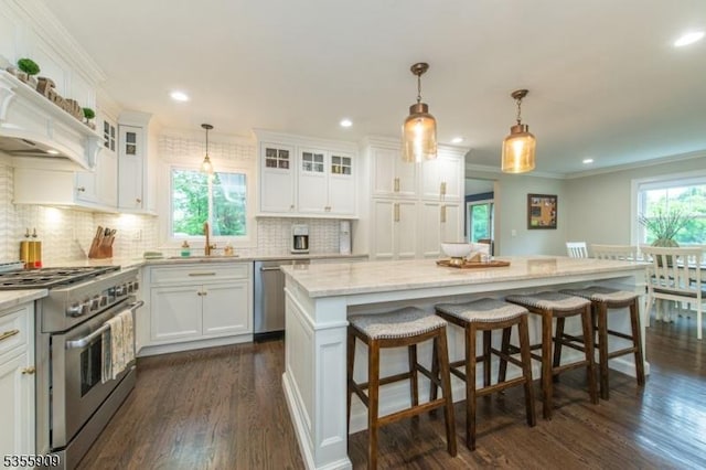 kitchen featuring stainless steel appliances, a sink, dark wood-type flooring, white cabinets, and tasteful backsplash