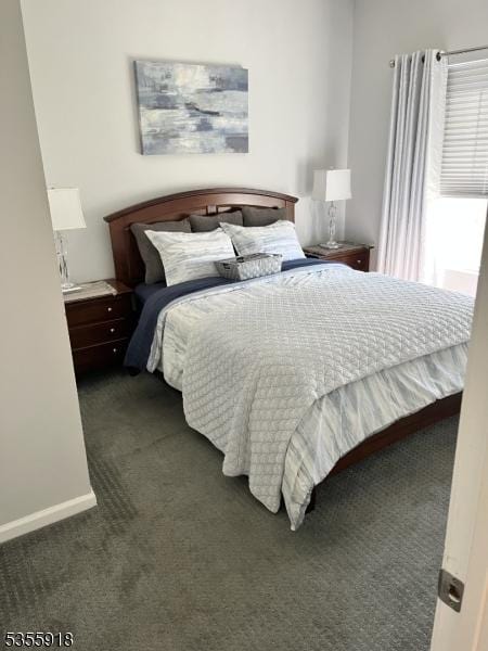 bedroom with dark colored carpet and baseboards