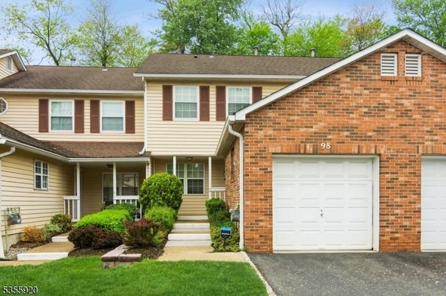view of property featuring brick siding, driveway, a garage, and roof with shingles