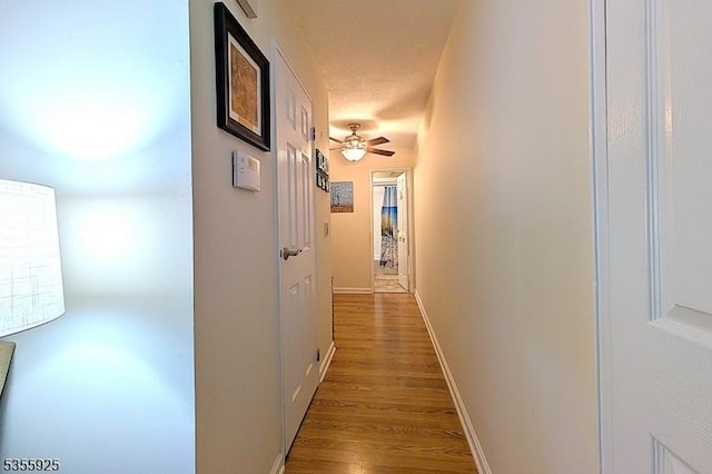 corridor featuring wood finished floors and baseboards