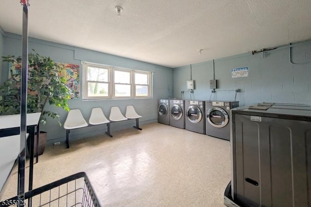 communal laundry room featuring washing machine and dryer and a textured ceiling