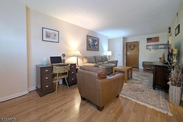 living room featuring light wood finished floors, baseboards, and an office area