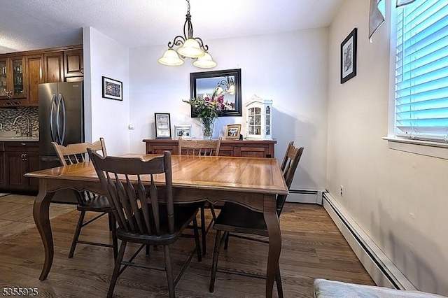dining space with wood finished floors, a baseboard radiator, and a chandelier
