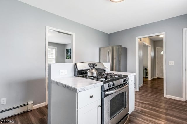 kitchen with appliances with stainless steel finishes, a baseboard radiator, baseboards, dark wood-style floors, and light countertops