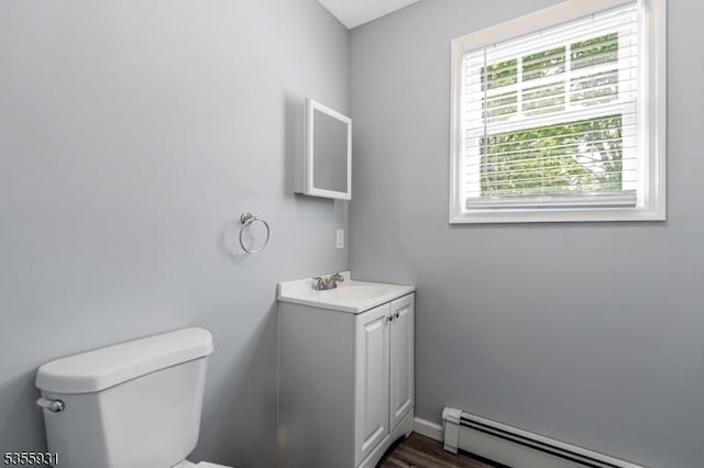 bathroom featuring a baseboard heating unit, toilet, vanity, and wood finished floors