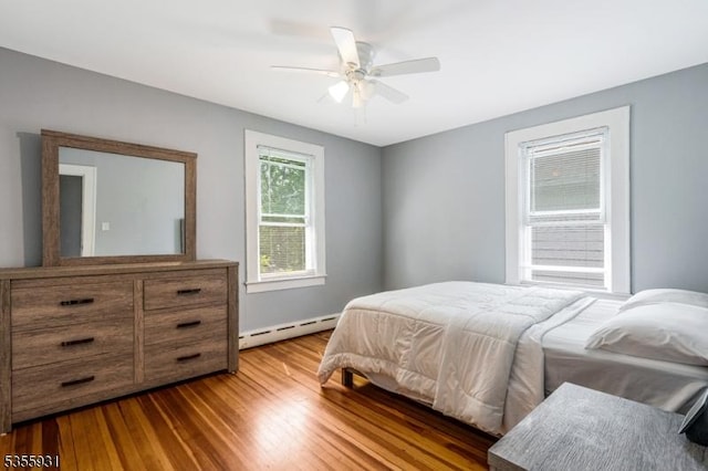 bedroom featuring a baseboard radiator, wood finished floors, and ceiling fan